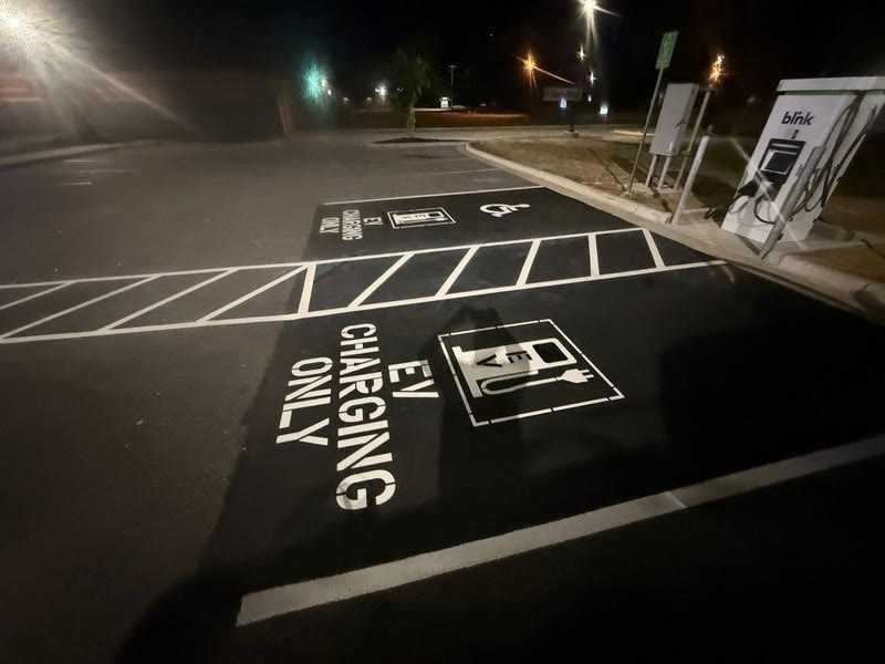 EV charging only stencil painted at night next to a charger